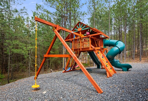 This awesome playset is a kid’s dream come true—complete with swings, a slide, climbing features, and tons of space to run around beneath the trees.