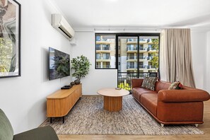 Relax in a stylish living room, featuring a comfortable orange sofa, modern furniture, and seamless access to a balcony.