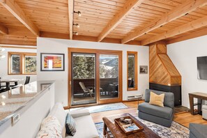 Living area with a fireplace, mounted TV, 2 twin sleeper sofas, and access to the private deck.