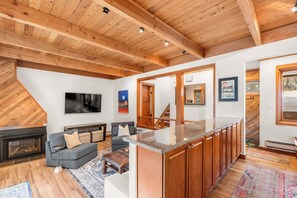 Living area with a fireplace, mounted TV, 2 twin sleeper sofas, and access to the private deck.