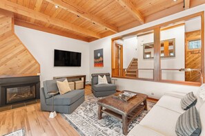 Living area with a fireplace, mounted TV, 2 twin sleeper sofas, and access to the private deck.