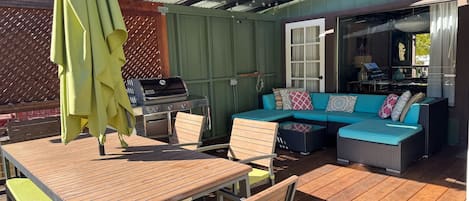 The covered back deck is outdoor living at its best! A BBQ, cozy seating, views, and a dining area.