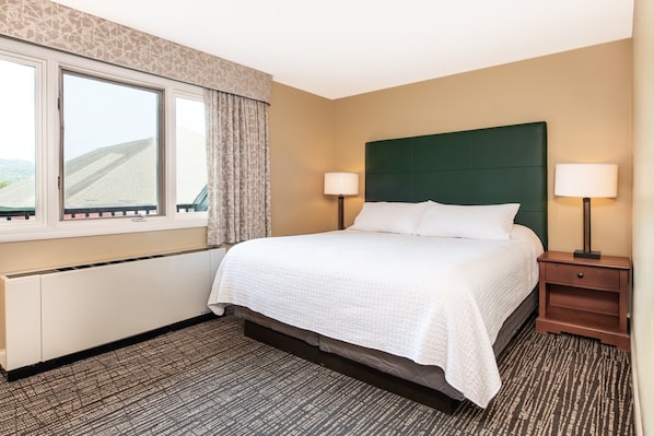 Relax in this bright and airy bedroom, featuring cozy bedding and large windows for plenty of natural light.