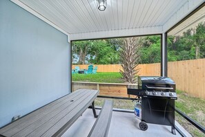 Screened in porch with picnic table and propane grill