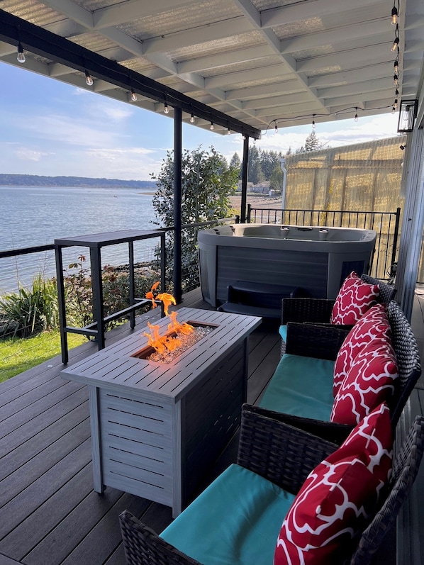 The deck is set up with patio furniture, dining table, hot tub, bbq.