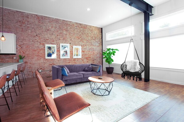 Spacious, light-filled living room with live plants and swing hammock chair!