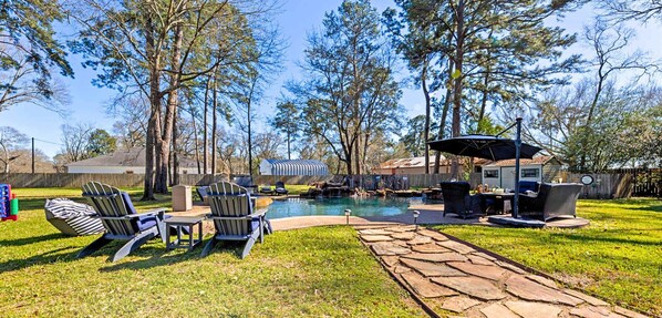 Backyard oasis with pool, lounge areas, and serene view