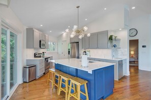 Fully equipped kitchen with modern appliances, ample counter space, and seating at the breakfast bar.