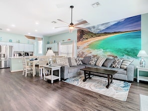 - Spacious open layout with a large beach mural that adds a serene coastal vibe
- Plush gray sectional and patterned pillows offer comfy seating for the whole group
- Full kitchen, dining set, and ocean toned decor perfect for gathering and relaxing