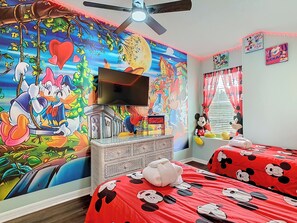 - Vibrant wall mural with Mickey, Minnie, Donald, and Daisy brings Disney charm to life
- Two twin beds with bold Mickey print bedding create a playful and cozy space
- Plush character toys and themed curtains complete this magical kids' retreat
