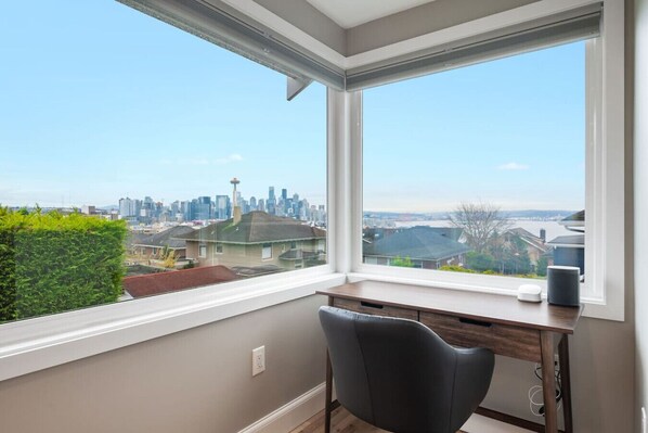 3nd FLOOR: A bright, peaceful workspace with a sleek desk, comfy chair, and a stunning Seattle skyline view—including the **Space Needle** and waterfront! ✨