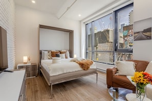 Comfortable queen Murphy bed framed by tall windows and thoughtful touches