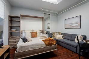 Stylish multifunctional space with a comfy bed, sofa, and warm, modern tones