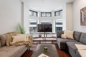 Bright bay windows frame this cozy lounge, perfect for streaming or unwinding in style