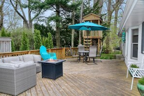 Backyard with mature trees, an expansive deck, and a wooden playhouse. 