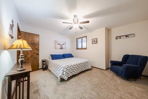 This queen bedroom includes a ceiling fan & comfy chair