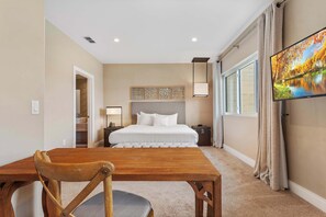 Spacious bedroom with king bed, workspace, natural light, and serene vibes
