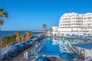 A stunning aerial view of a pool stretching towards the sea, lined with loungers for sun-soaked relaxation.