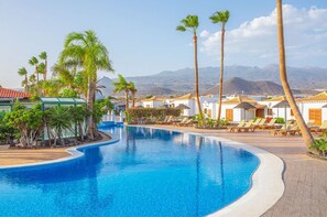 Escape into a serene pool haven, surrounded by lush palms and under clear skies for peak relaxation.