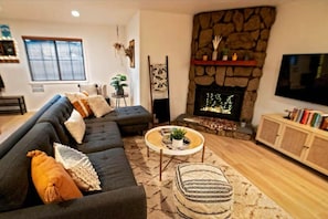Cozy living space, featuring a stone fireplace, plush seating, and inviting decor.