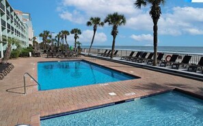 Relax by oceanfront pool with loungers and palms, steps from the beach