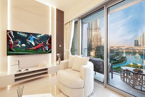 Relax in the cozy living room featuring a comfortable armchair, smart TV, and PlayStation for your entertainment. Enjoy the stunning views of Downtown Dubai, creating the perfect blend of comfort, fun, and luxury