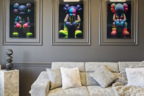 Three Bearbricks portraits add a bold, artistic flair above the plush sofa bed, creating a trendy and vibrant vibe in this luxury Downtown Dubai vacation rental.