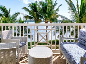 Private balcony with cozy seating offers stunning views of swaying palms and the tranquil outdoors.