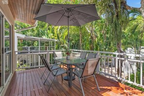 Enjoy laid-back afternoons on the private balcony, savouring fish and chips at the outdoor dining table, perfectly shaded beneath an umbrella.