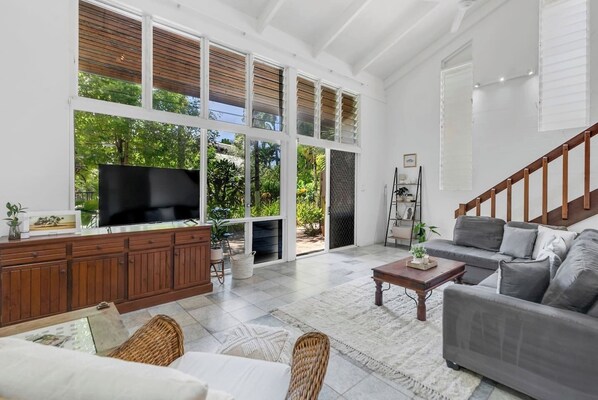 Kick back and relax in the main living area, where lush greenery peeks through the windows, and movie nights on the L-shaped sofa feel like home.