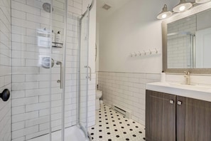 A modern and stylish bathroom featuring a glass-enclosed shower, elegant subway tile, and a spacious vanity for a refreshing start to your day.