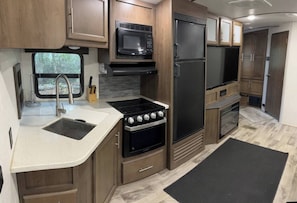 Kitchen is equipped with fridge, freezer, stove top, oven microwave, coffee maker.