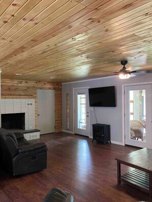 Living room hosts large leather sectional sofa, recliner, electric fireplace, big screen TV