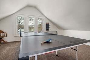 Game room with couch, smart tv, video games, board games, ping pong, and air hockey tables.