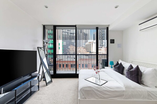 A cozy studio with a queen sized bed & plush pillows.