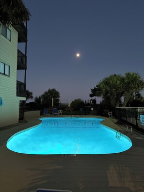 Relax by a moonlit pool, illuminated by the underwater lights.