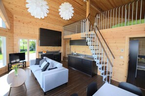 TV, sofas, coffee table, kitchen area, stairs up to sleeping area