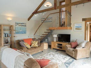 Living area with sofas, armchair, tv, stairs to first floor