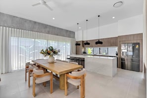 Share delicious meals at the striking timber dining table, where a ceiling fan overhead ensures a comfortable setting for relaxed gatherings and lively conversations.