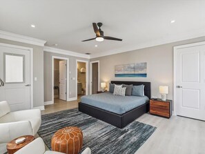 A luxurious primary bedroom, featuring ample space and a cozy seating area.
