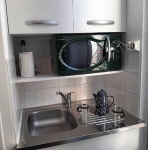 Une petite kitchenette avec juste un micro-ondes et un frigo