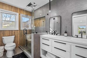 Stylish spa-like bathroom with a sleek double vanity, glass shower, and natural light.