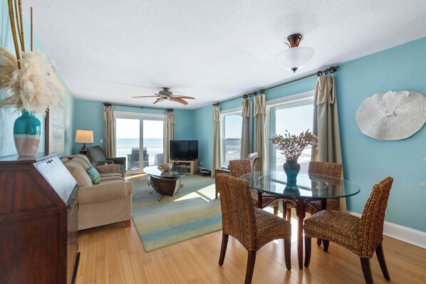 Living room and dinette with windows on both walls with views of the beach.