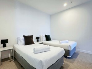 The second bedroom with a two single sized bed and plush pillows.