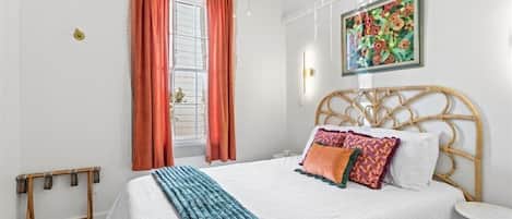 Cozy pillows and throw complement colorful local art above this queen-sized bed. You'll rest well amid these luxurious linens!
