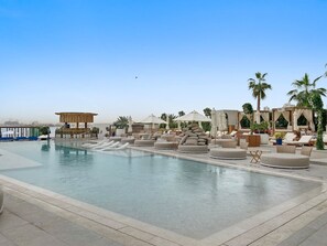 Outdoor Oasis: Splash into relaxation at the stunning pool surrounded by luxe cabanas and palms!