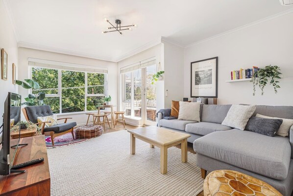 Lounge in the Scandi-styled living area, where an L-shaped sofa, armchair, and Moroccan-style leather ottoman create the perfect spot to relax with a book or your favourite film.