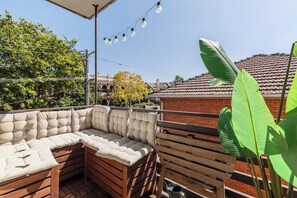 Step outside to your private balcony, where cushioned seating, a foldable table, string lights, and treetop views create a perfect setting for morning coffee or evening drinks.