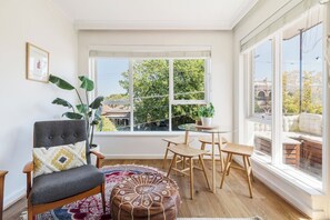 Gather around the glass dining table, where minimalist wooden chairs and leafy views create a peaceful setting for meals or planning your next adventure.