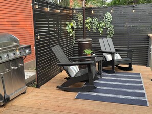 Patio includes gas grill and outdoor heater nearby a trickling pond fountain